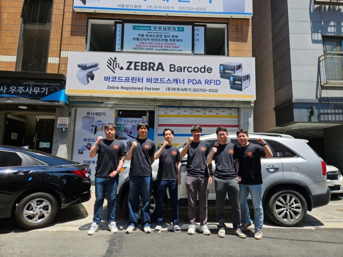 ZEBRA Barcode와 Zebra Registered Partner 간판이 걸린 우주사무기 매장 앞에 선 직원들